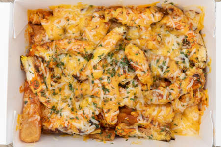 Overhead view of hearty side order of buffalo chicken french fries covered in cheese and served in a take out box to eat on the go.の写真素材