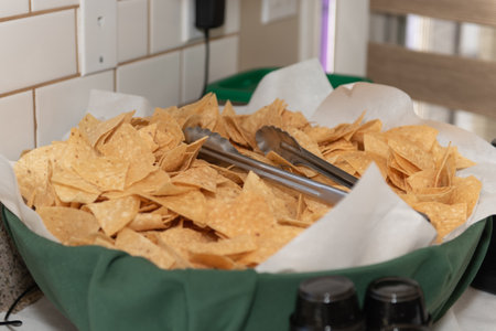 Large bowl of chips with serving tongs ready for the party guests to serve themselves.