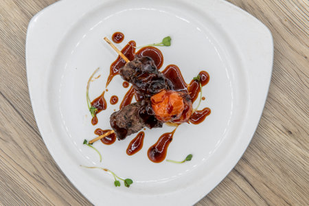 Overhead view of tempting appetizer of glazed beef skewers served on a small plate.
