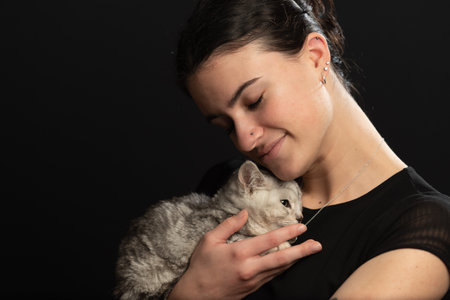 Egyptian Mao kitten snuggles against young lady as they enjoys each others warmth.