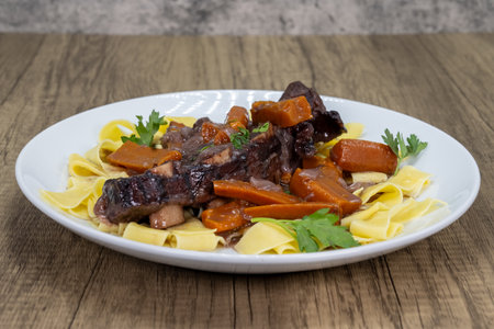 Braised short ribs over pasta and carrots, cooked to perfection.の写真素材