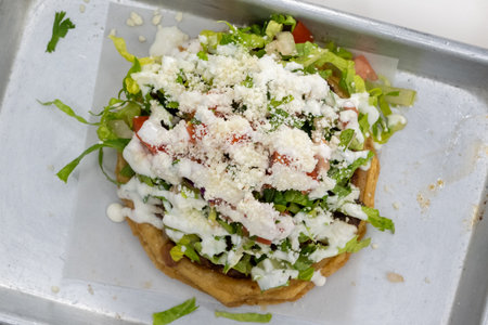Overhead view of mouth watering Asada Sope meal overloaded with meat, cheese, and lettuce on a...