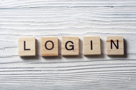 LOGIN word written on wood block at wooden background.の写真素材