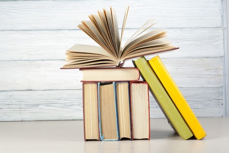 Open book, hardback books on wooden table.