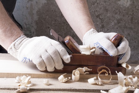 Carpenter working with plane on wooden background at Building Site. Carpenter workplaceの写真素材