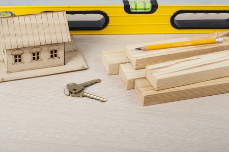 Model house and construction tools ,keys on a wooden tableの写真素材