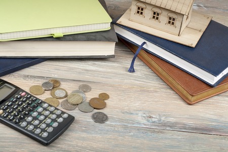 Home savings, budget concept. Model house, notepad, calculator and coins on wooden office tableの写真素材