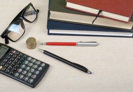 Home savings, budget concept. Notepad, calculator,pencil, eyeglasses and coins on wooden office tableの写真素材