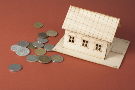 Home savings, budget concept. Model house and coins on a colorful background.の写真素材