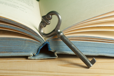 Key to knowledge concept. Book with key on wooden background.の写真素材