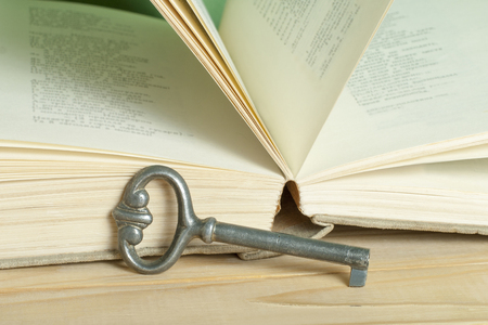 Key to knowledge concept. Book with key on wooden background.の写真素材