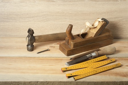 Carpentry concept.Joiner carpenter workplace. Old planer,hammer ,chisel ,meter and pencil on wooden...