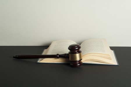 Law concept. Wooden judge gavel and open book on table in a courtroom or enforcement office.
