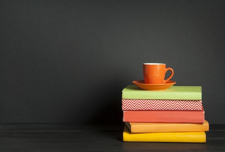 Stack of colorful books and cup of coffee on the wooden table. Education background. Back to school.Copy space for text.の写真素材