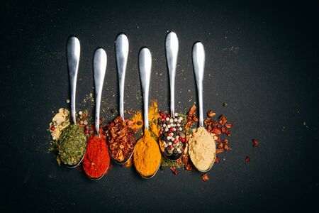 Various herbs and spices on black plate