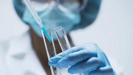 Medical worker adding few drops of blue liquid into test tubes, chemistryの写真素材