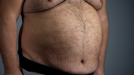 Big belly of unhealthy adult man junk food overeating problem overweightの写真素材
