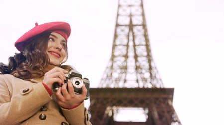 Creative girl holding camera in hands, enjoying photography hobby in Parisの写真素材