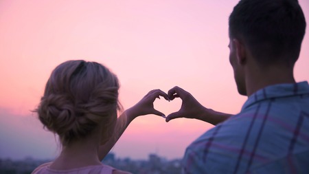 Lovers putting their hands together in shape of heart, demonstrating their loveの写真素材