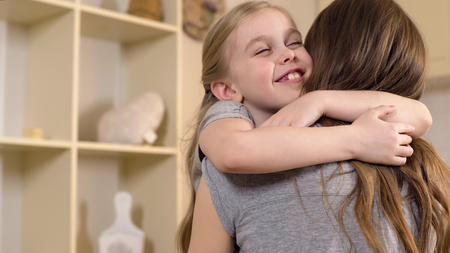 Happy little girl smiling and hugging mother with love, warm childhood memories, stock footageの写真素材