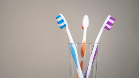 Three colored toothbrushes stand on shelf in bathroom, care for oral cavity, stock footageの写真素材
