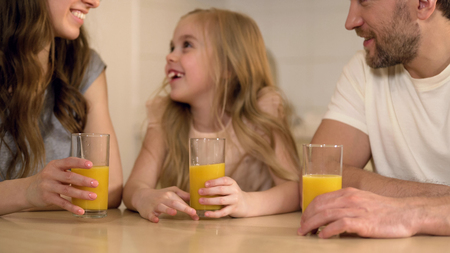 Happy healthy family drinking orange juice with smiles on faces, morning at home, stock footageの写真素材