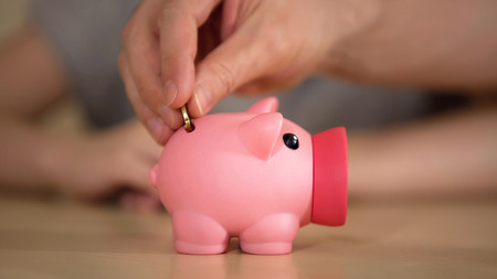 Father and kid putting money in piggy bank for purchase, saving family budget, stock footageの写真素材
