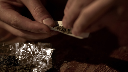 Male hands making joint, rolling marijuana into cigarette, drug legalization, stock footageの写真素材