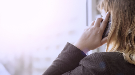 Businesswoman looking out of window while having conversation over mobile phone, stock footageの写真素材