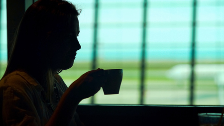 Young lady sitting at airport restaurant and enjoying hot coffee, tourismの写真素材
