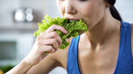 Wishing lose weight and be slim, lady making herself eating lettuce, nutritionの写真素材