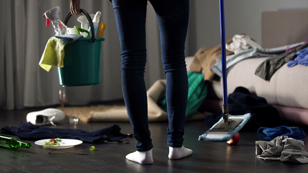 Shocked cleaning lady standing in messy hotel room with mop and washing bucketの写真素材
