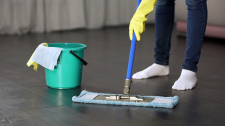 Obsessive with cleanliness young lady thoroughly washing floor of her houseの写真素材