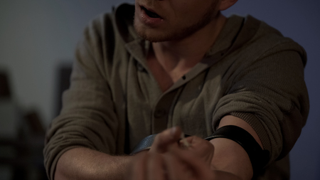 Intoxicated young man enjoying himself while injecting drug dose with syringeの写真素材