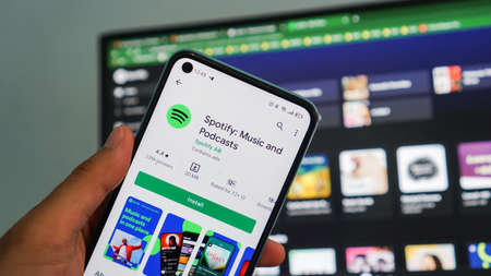 Dumai, Indonesia - 09 November 2021: holding smartphones opening spotify app, Spotify is a music service that offers legal streaming music.のeditorial素材