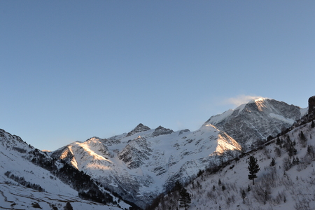 Beautiful evening in the mountains. Evening sun rays. Amazing view to evening snowy mountains. Nice winter landscape.の写真素材