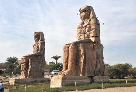 Tourist staring in wonder at the  the two colossi of memnon at the entrance to the valley of the kings at thebes near Luxor, Egyptの写真素材