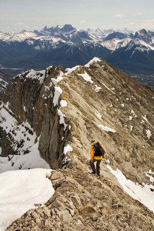 Young man moving along an exposed ridge in the Canadian Rocky Mountains in the Springの写真素材