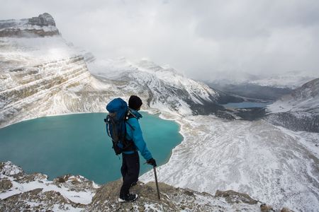 Young man stands high above alpine lake in the Rocky Mountains, Banff National Park, Alberta, Canada.の写真素材