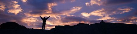 Silhouette of person with raised arms against dramatic sunset sky, Norway, Scandinaviaの写真素材