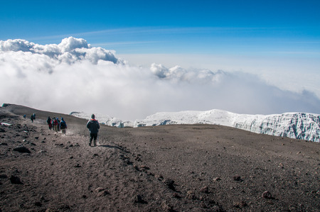 Walking back along the rim of the crater above the glaciers to Stella Point and the descent route back to camp at Barafuの写真素材