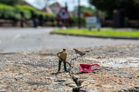 Miniature people, a workmen 5repairing a crack in the road in Lennoxtown, Scotlandの写真素材