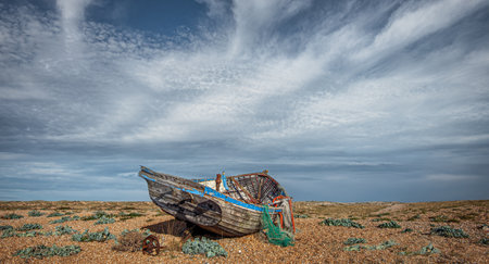 On the shingle beach of Dungeness Headland in Kent are several old, abondoned fishing boatsの写真素材