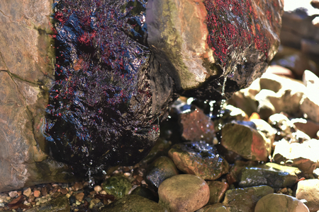 Water fountain in park, the water is flowing on a rock.の写真素材