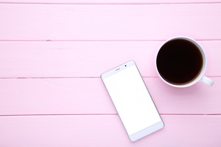 Smartphone with cup of coffee on pink wooden background. Smartphone with white screen.の写真素材