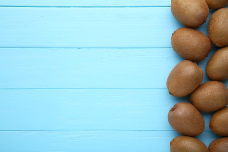 Fresh kiwi fruit on blue wooden background, flat layの写真素材