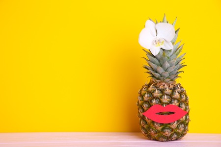 Ripe pineapple with orchid and lips on a yellow backgroundの写真素材