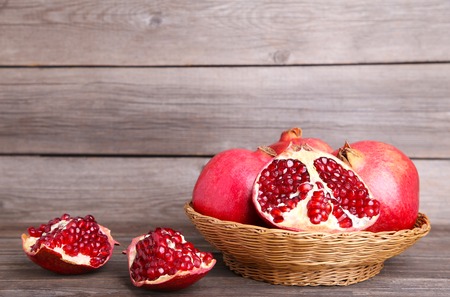 Ripe pomegranates on basket on grey backgroundの写真素材