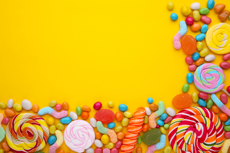 Colorful lollipops and different colored round candy on yellowの写真素材