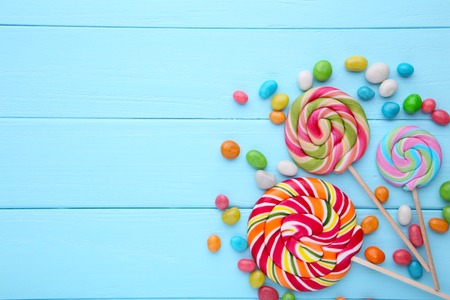 Colorful lollipops and different colored round candy on blue